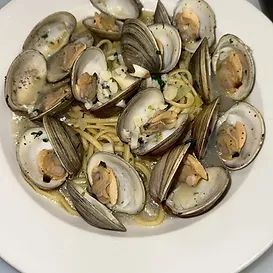 Plate of linguine with clams, garnished with herbs.