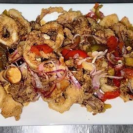 Fried calamari with red onions, peppers, and lemon on a white plate.