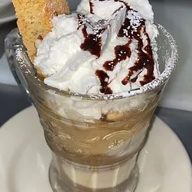 Coffee dessert in a glass, topped with whipped cream, chocolate sauce, and cookie.