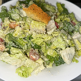 Caesar salad on a white plate: romaine lettuce, croutons, parmesan, and dressing.