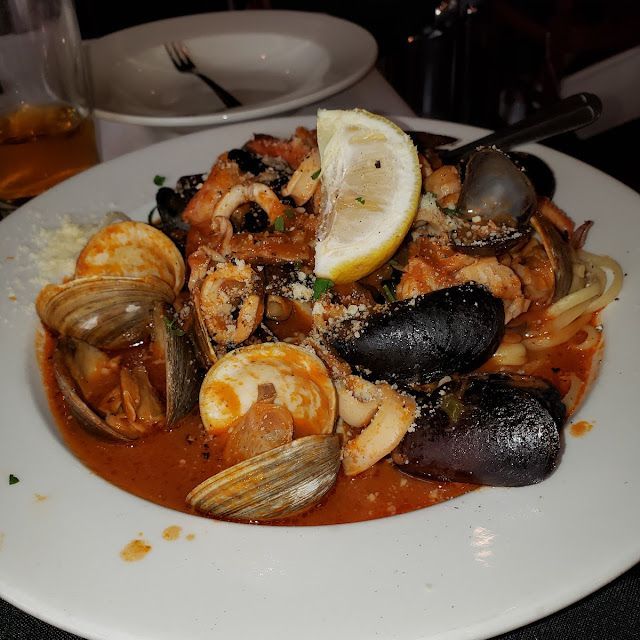 Seafood pasta dish with clams, mussels, and lemon wedge on a white plate.