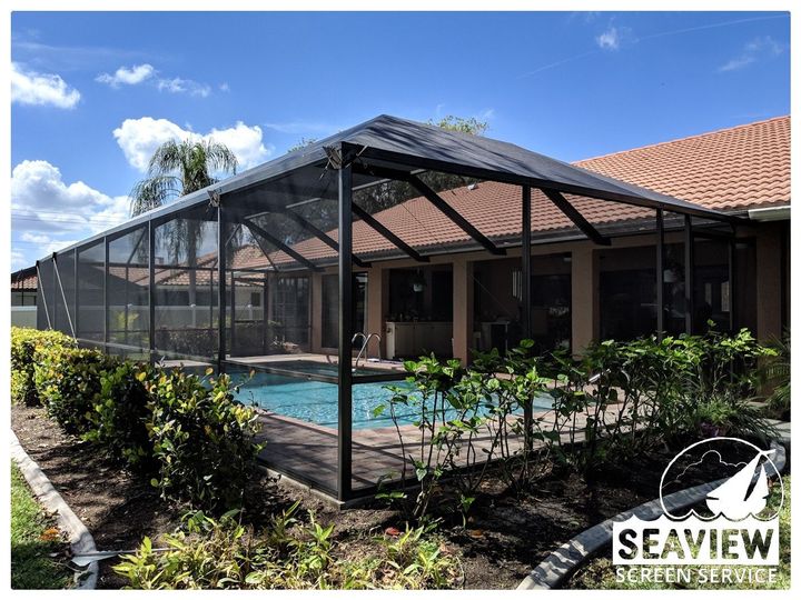 A screened in porch with a lot of windows and a ceiling fan.