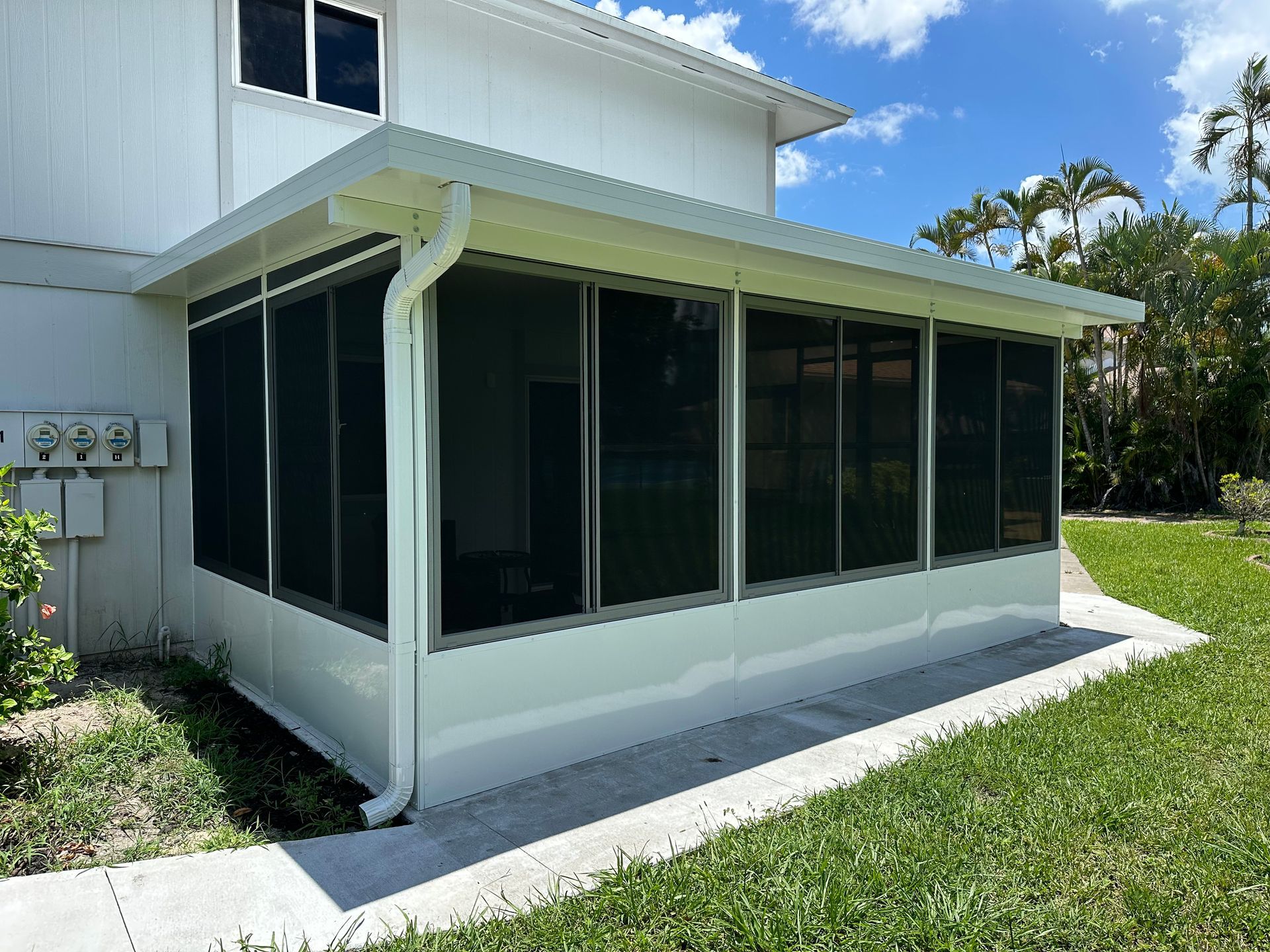 A screened in porch on the side of a white house.