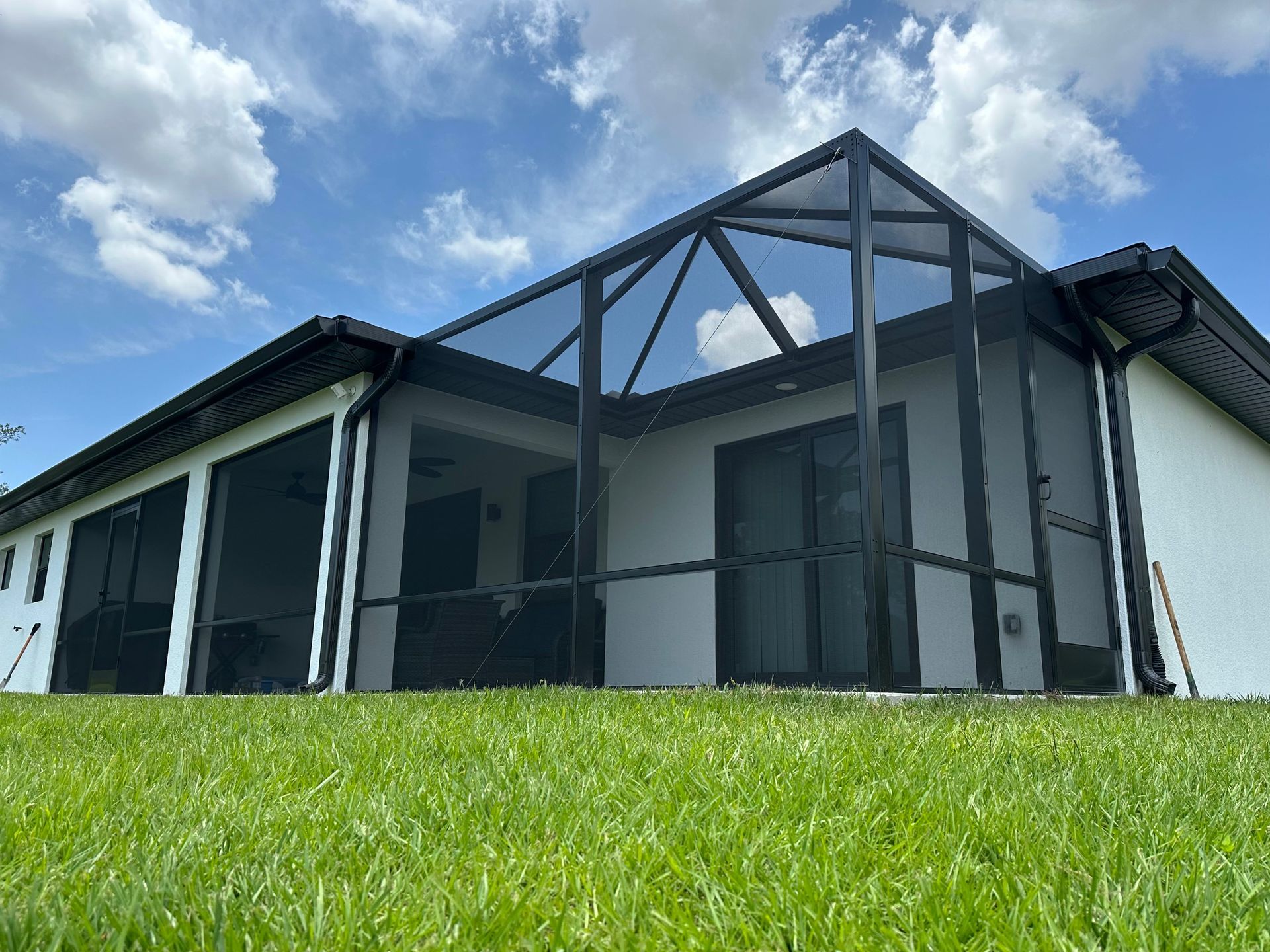 A house with a screened in porch is sitting on top of a lush green hill.