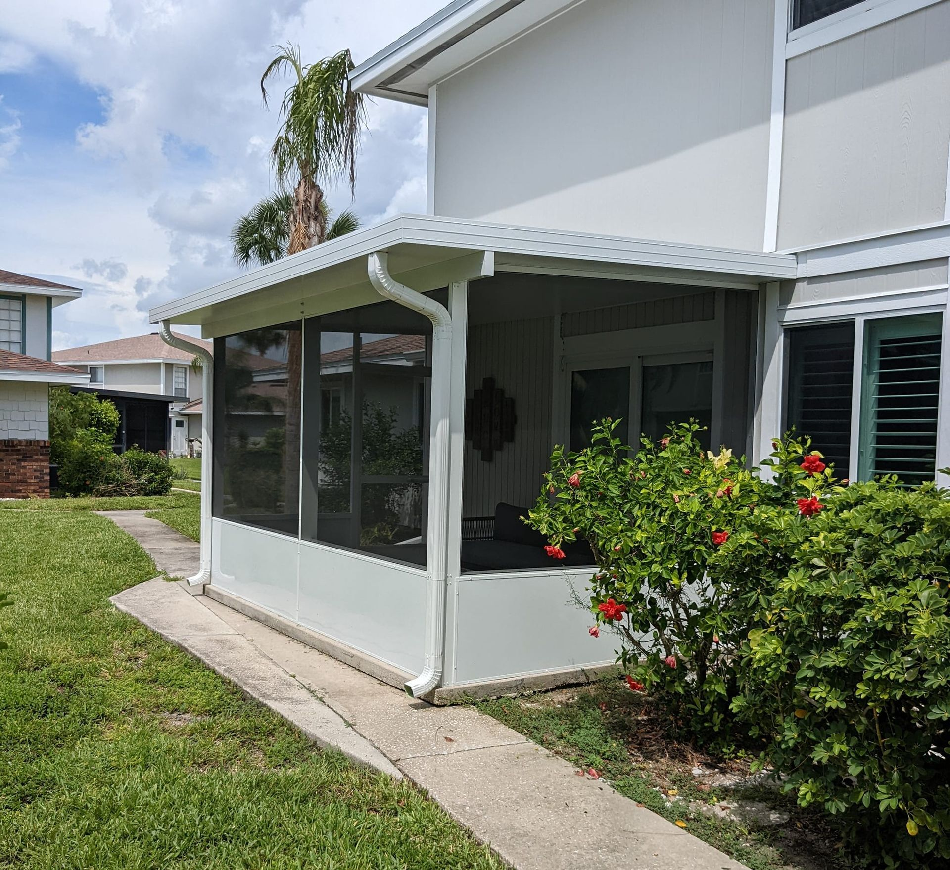 A white house with a screened in porch in the backyard