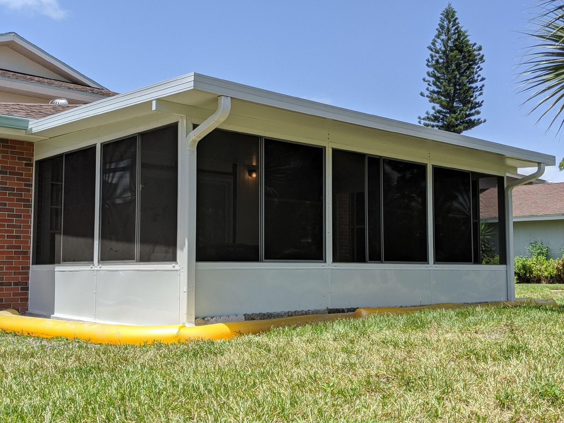 A screened in porch in the backyard of a house