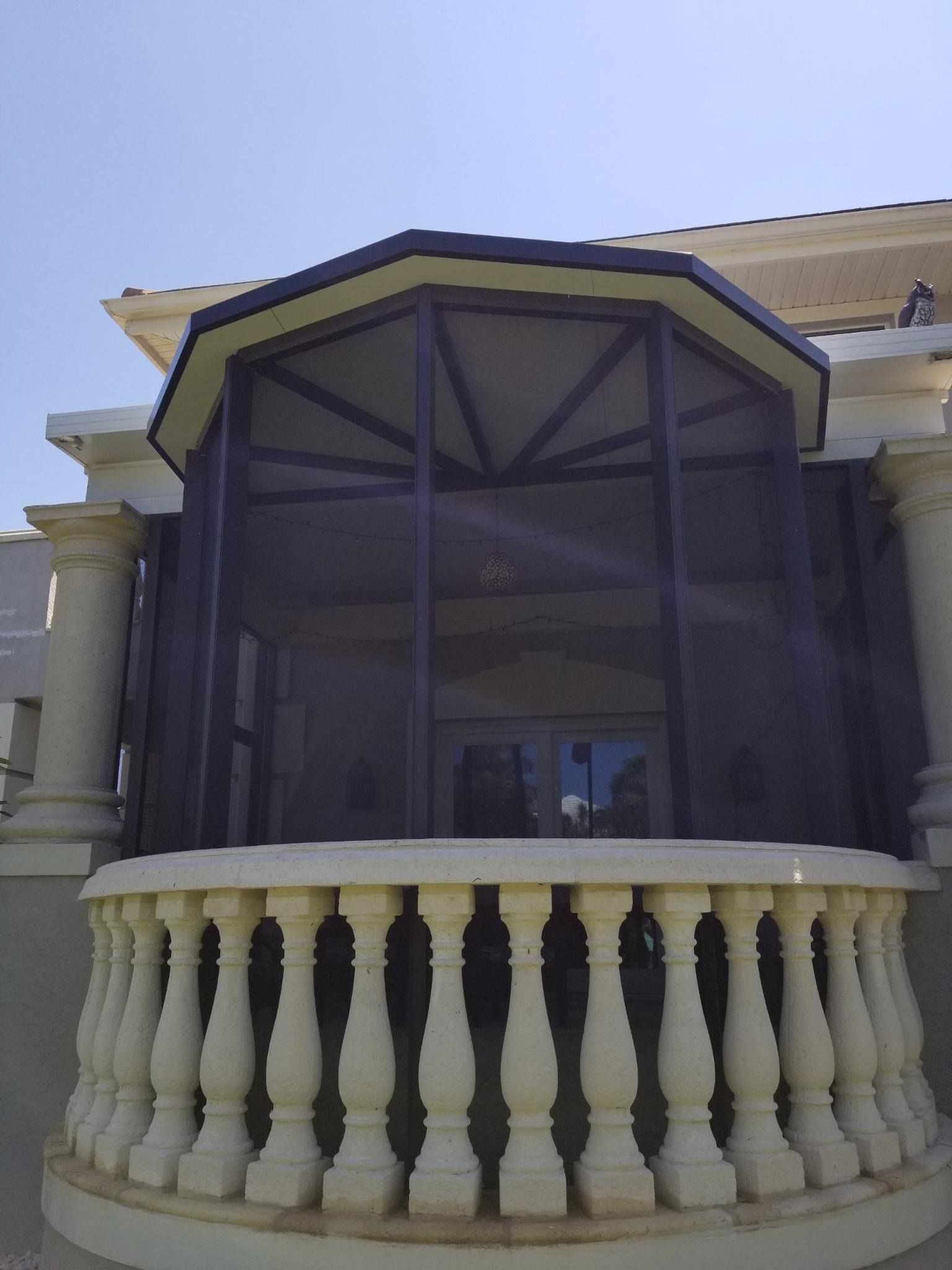 A screened in porch with a balcony and columns