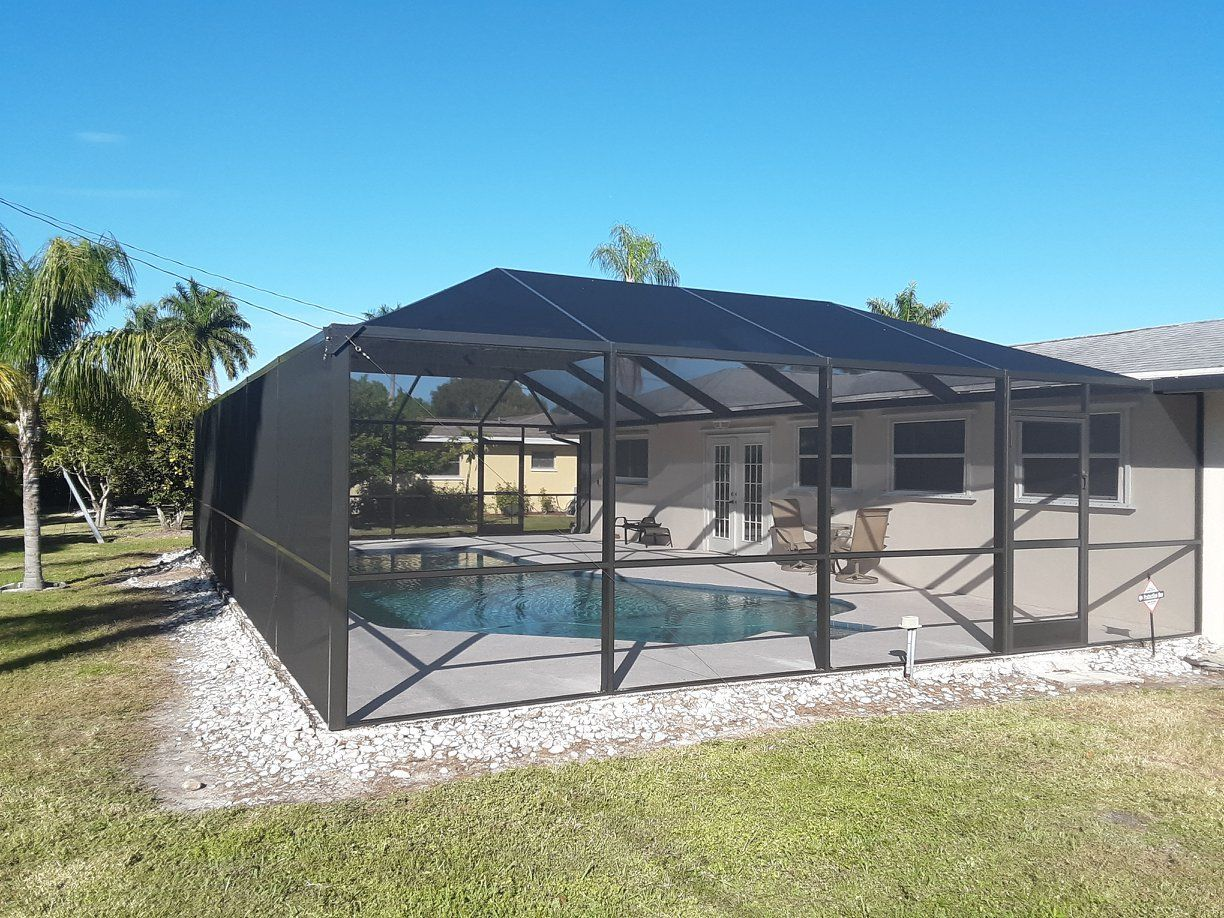 A screened in patio with a pool in the backyard of a house.