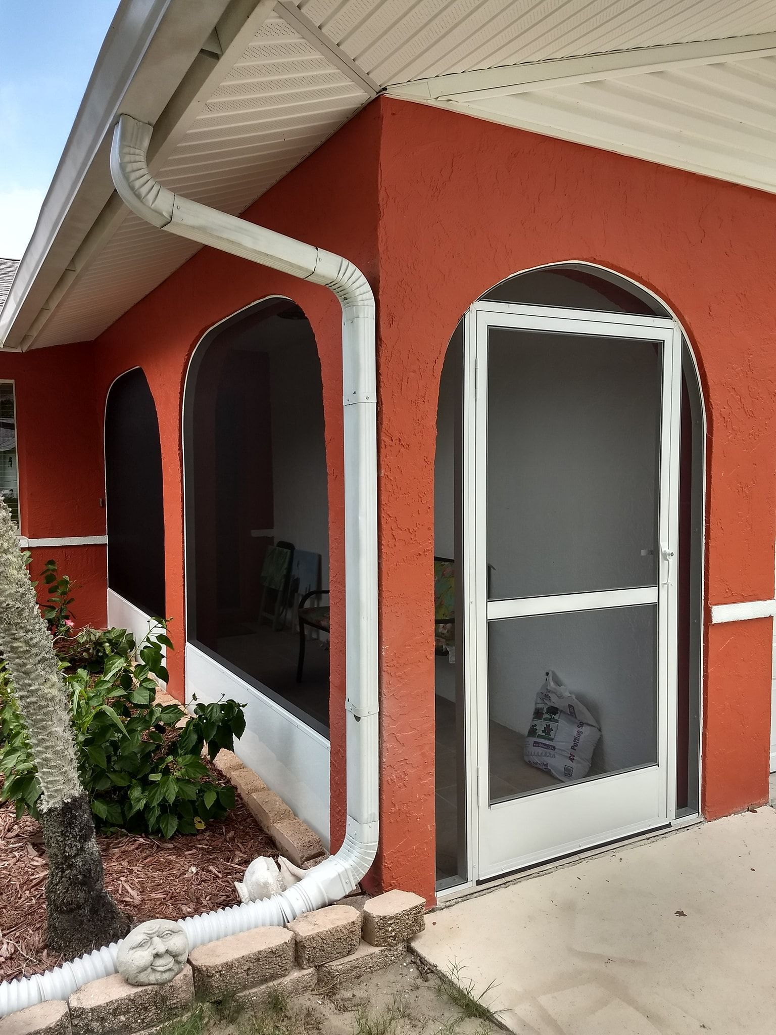 An orange house with a screened in porch and a white door