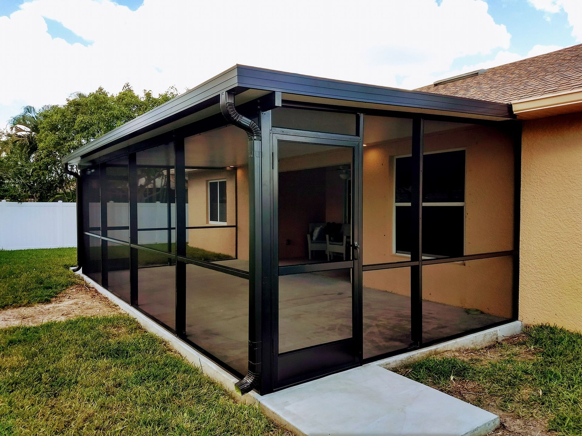 A screened in porch in the backyard of a house.