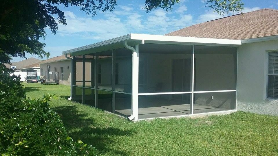 A screened in porch in the backyard of a house