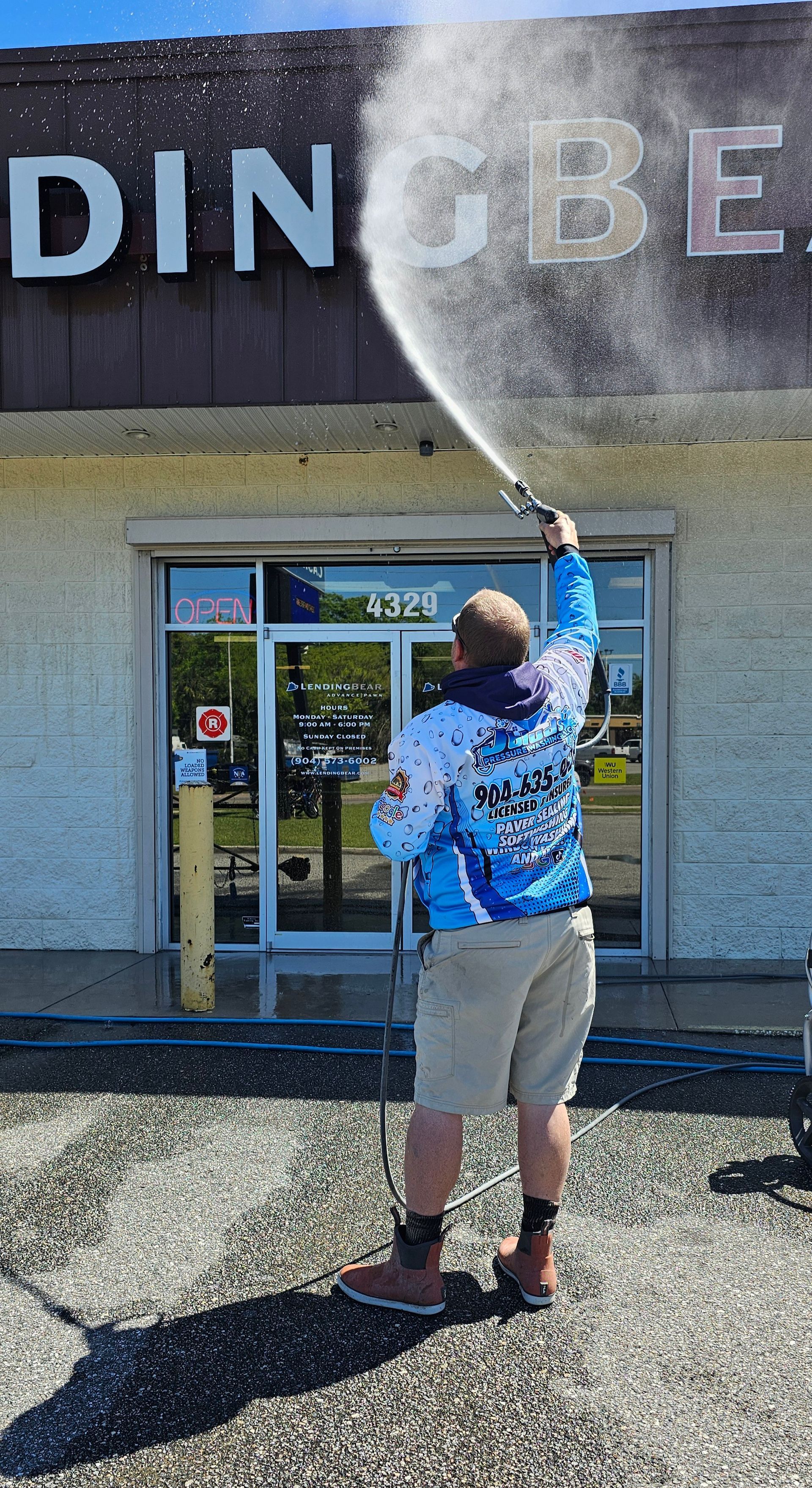 Person power washing the sign of a business.