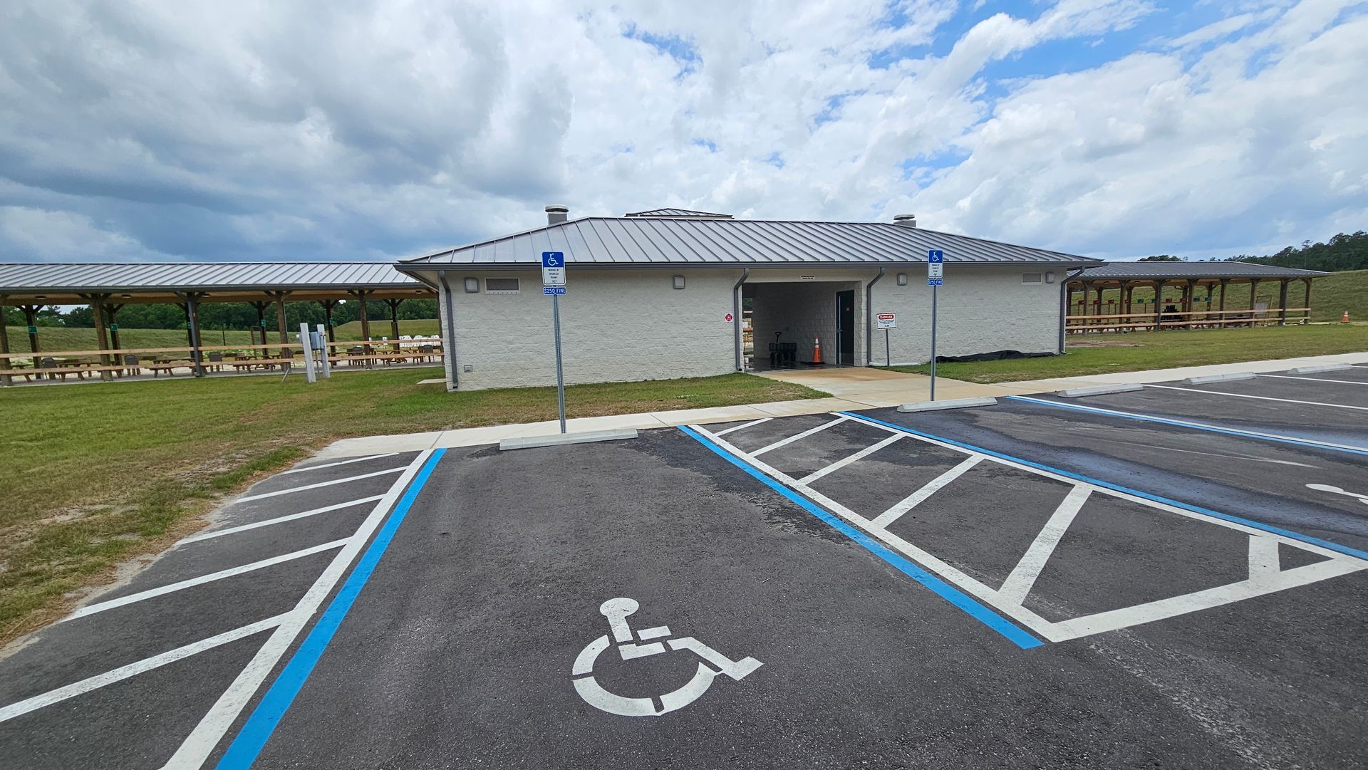Accessible parking spaces in front of a brick restroom building with a blue disabled parking sign.