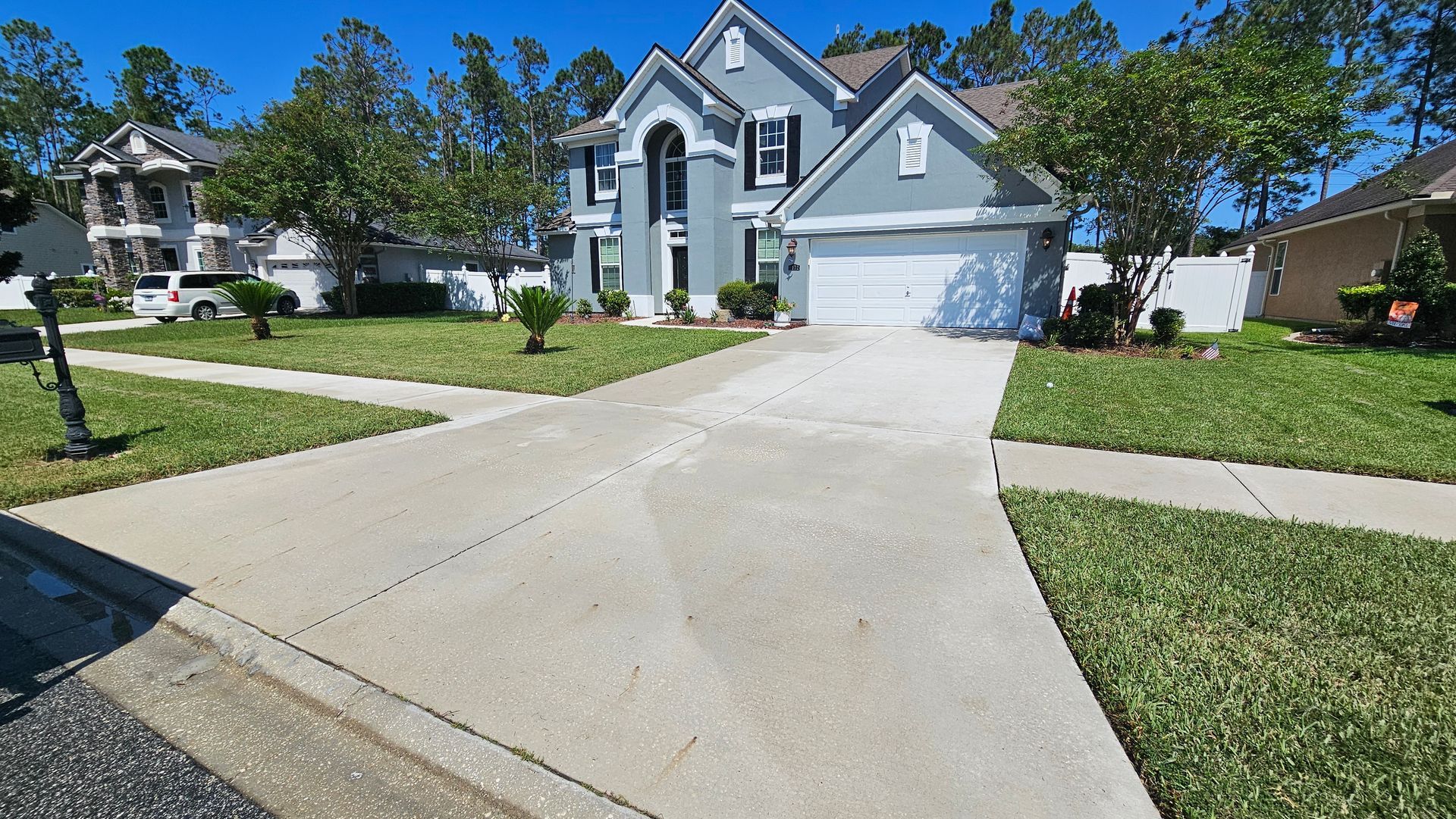 A two-story gray house with a white garage door and a long driveway.