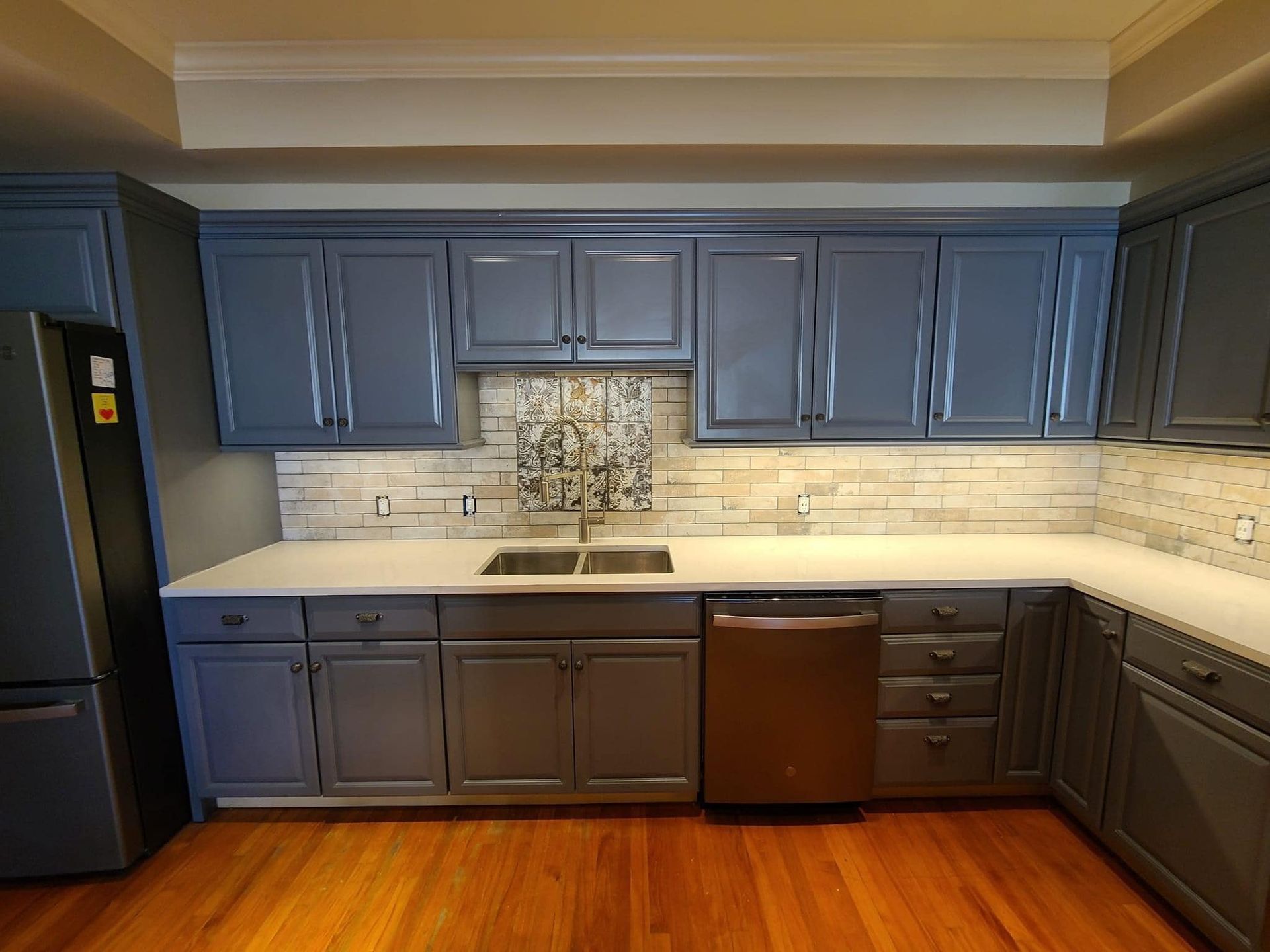 Kitchen with blue-gray cabinets, white countertops, stainless steel sink, and a copper dishwasher.