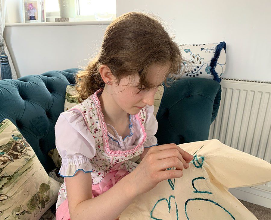 a girl embroidering a tote bag