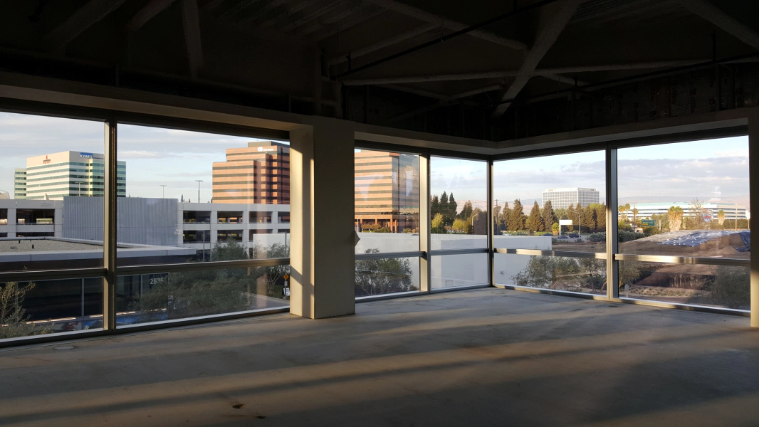 An empty room with a lot of windows and a view of a city.