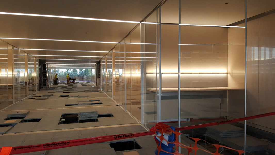 A long hallway with a lot of glass walls and a red tape.