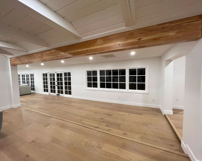 A large empty room with hardwood floors and white walls.