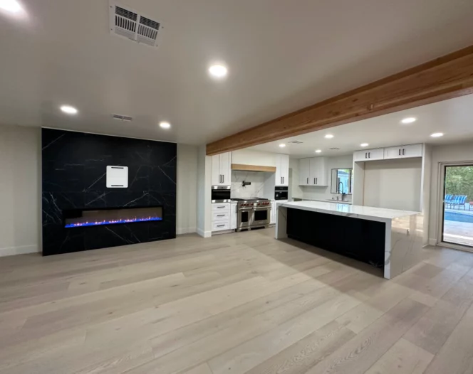 An empty living room with a fireplace and a kitchen