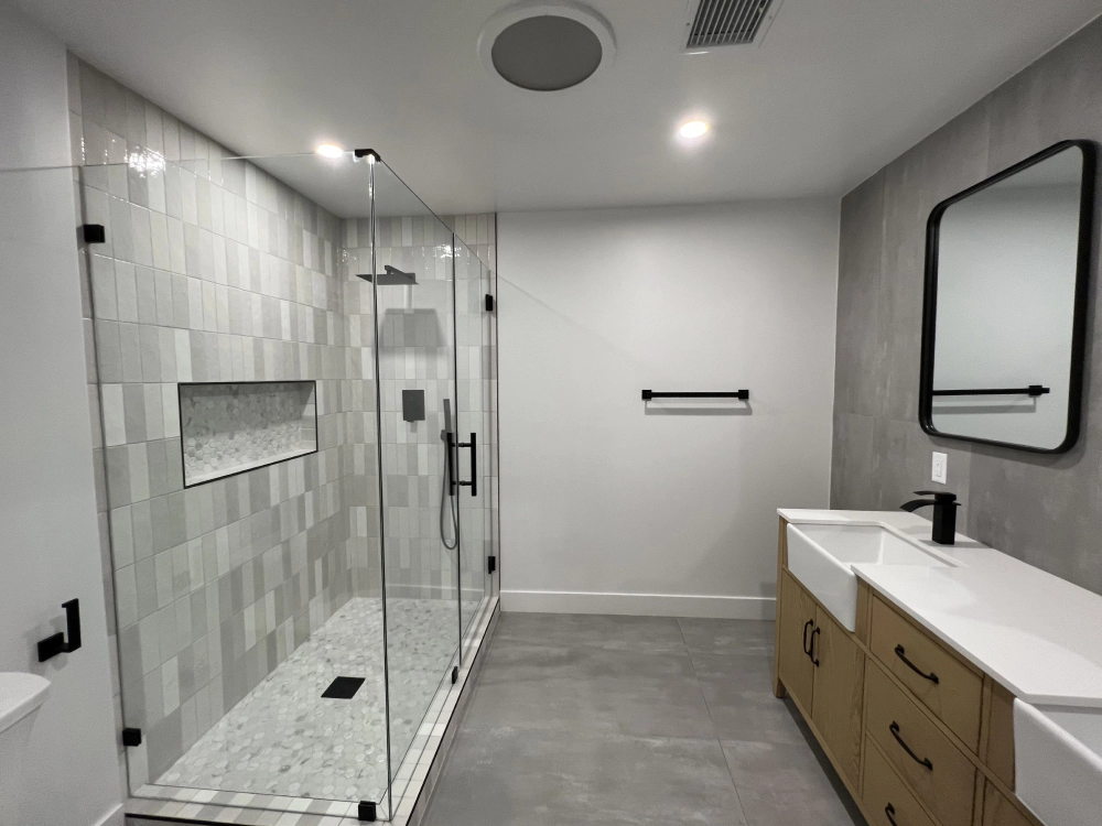 A bathroom with a walk in shower , sink and mirror.