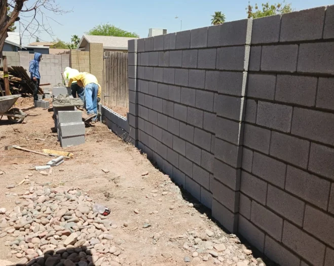 A brick wall is being built in a backyard