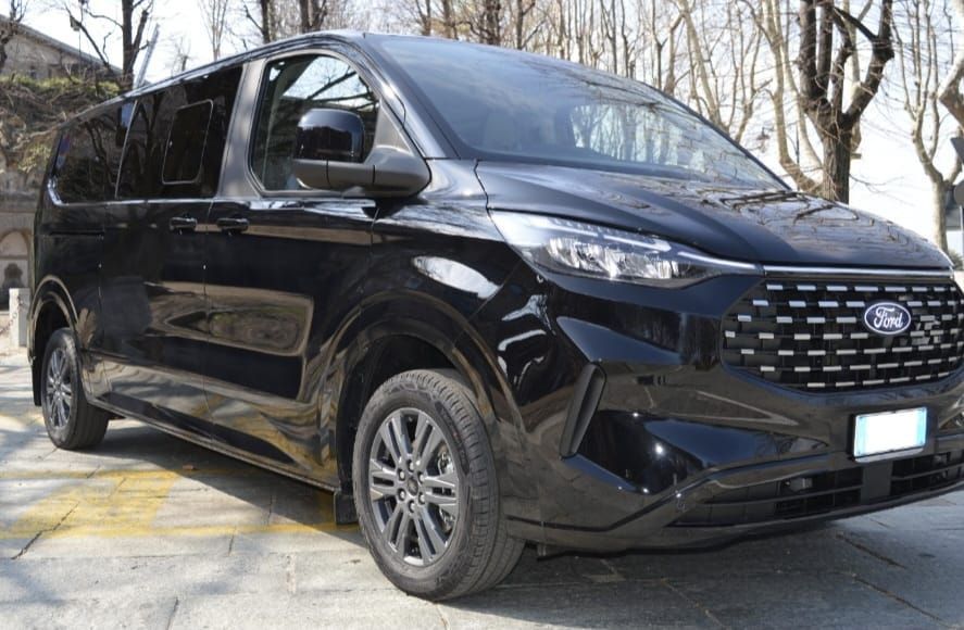 Uomo alla guida di un furgone, vista panoramica della campagna visibile attraverso il parabrezza.