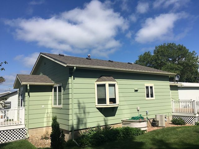 A green house with a gray roof and white windows