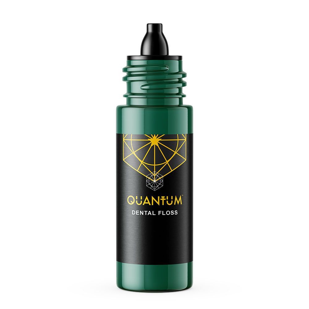 Bottle of Quantum dental floss with black cap and green label, featuring a gold geometric design.