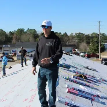 A man wearing sunglasses and a hat is walking on a roof