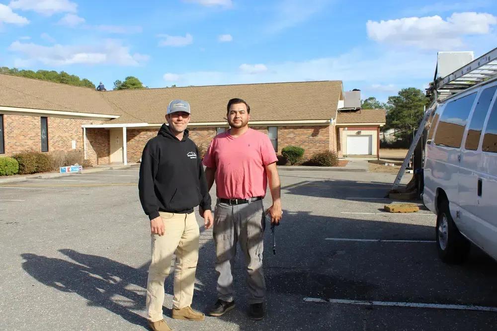 Two men are standing in a parking lot next to a van.
