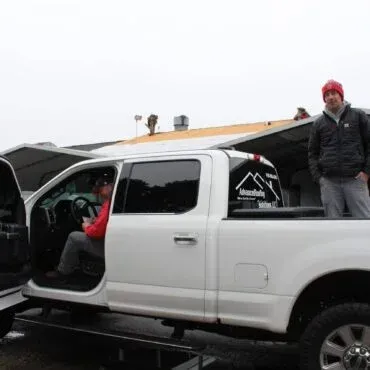 A man is standing next to a white truck with the door open.