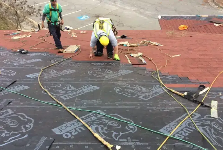 Two construction workers are working on a roof.