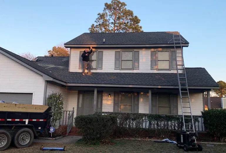 A man is working on the roof of a house.