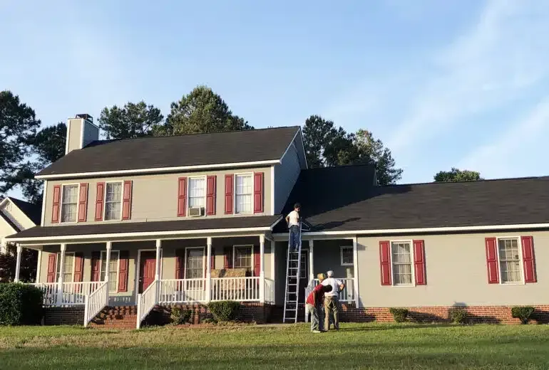 Two people are painting the roof of a house.