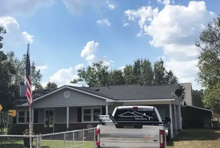 A white truck is parked in front of a house with an american flag.