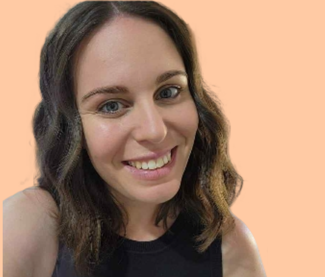 Smiling woman with wavy brown hair, blue eyes, and fair skin against an orange background.