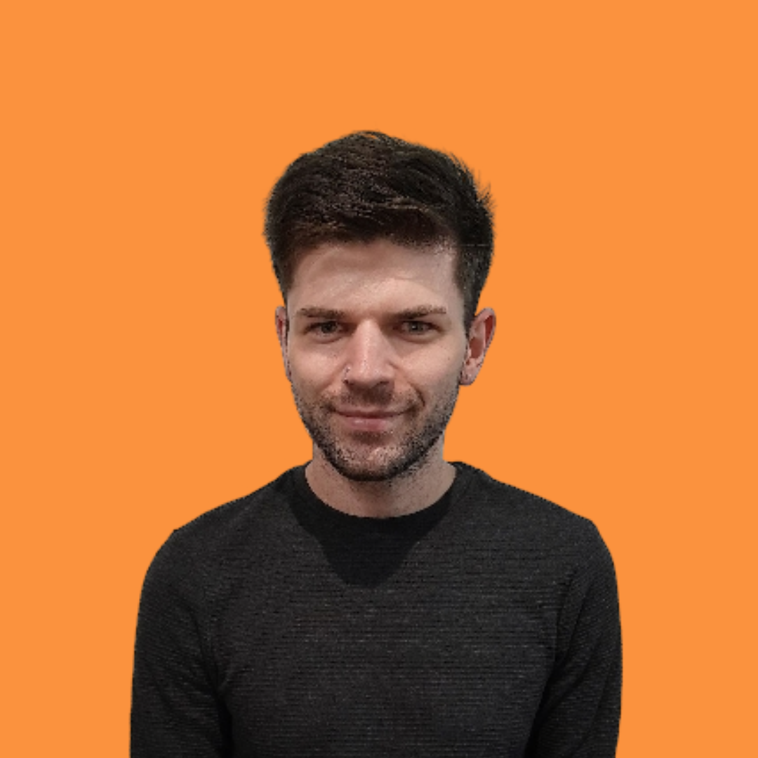 Man with dark hair and stubble smiling, wearing a black shirt, orange background.