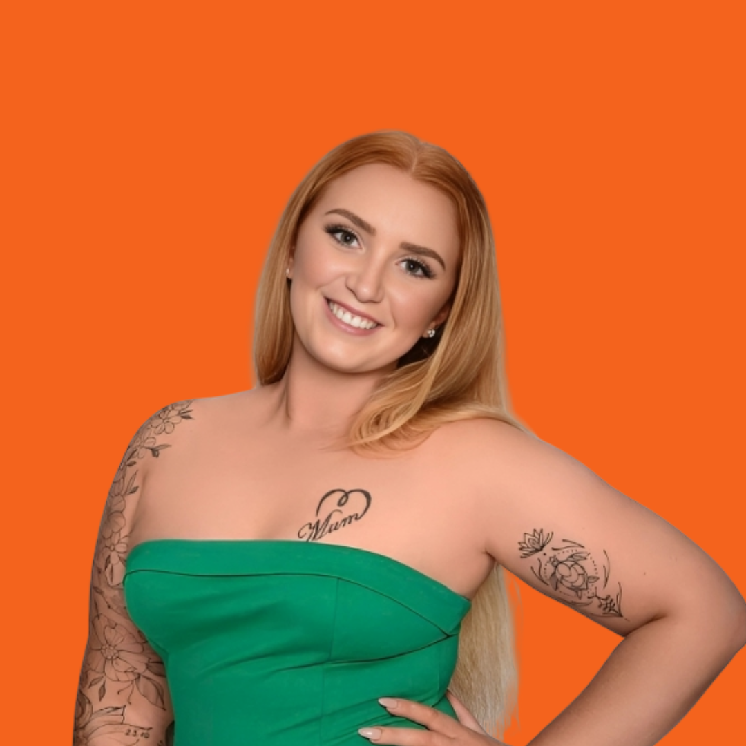 Woman with blonde hair, green dress, tattoos, smiling at the camera against an orange background.