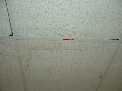 A white tiled ceiling with a red sign on it.