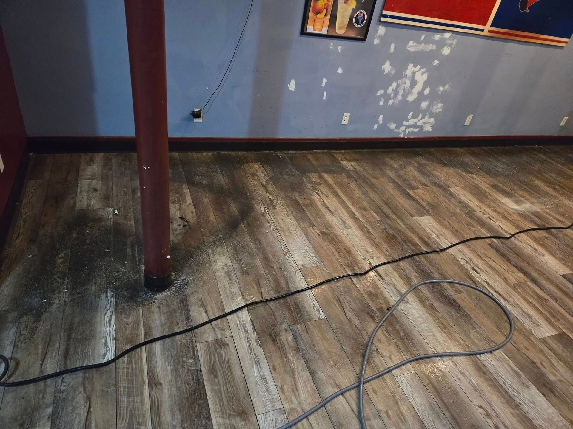 A room with a wooden floor and a cord on the floor.