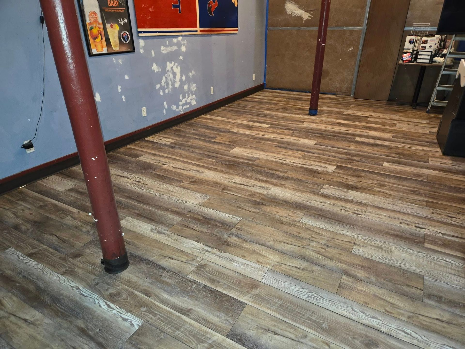 A room with a wooden floor and a purple wall.