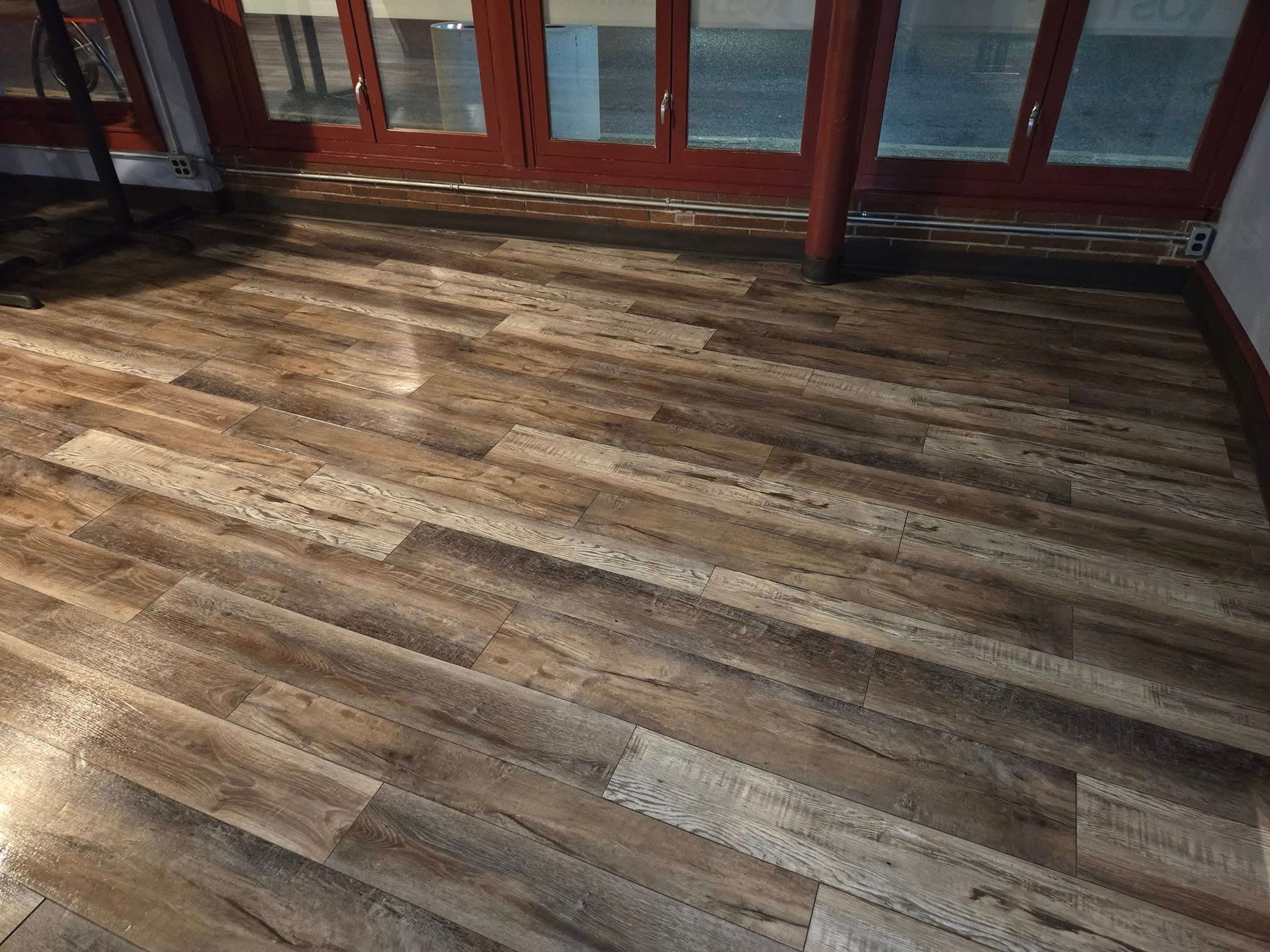 A wooden floor in a room with a lot of windows.