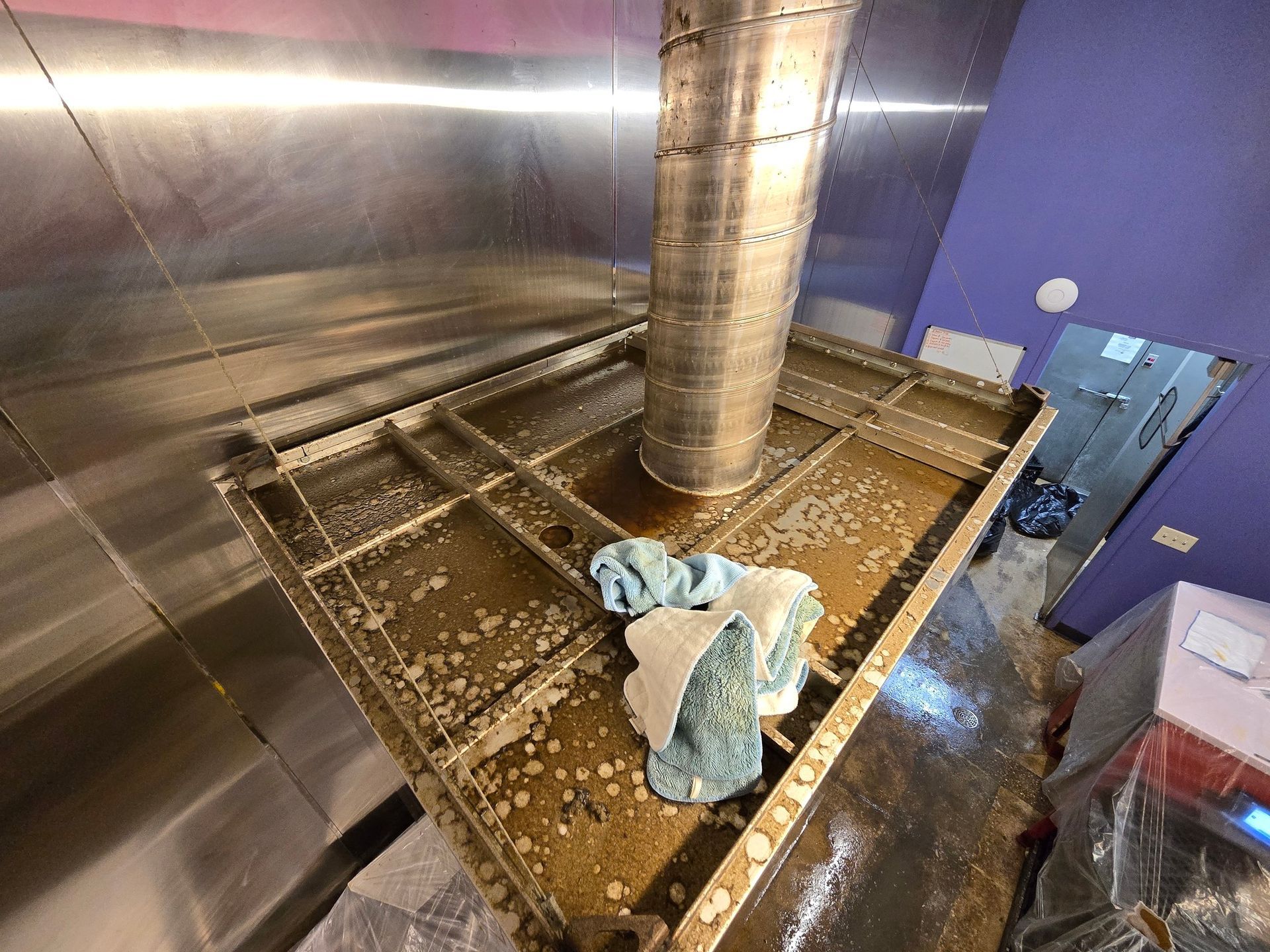A dirty room with a stainless steel wall and a pipe in the middle.