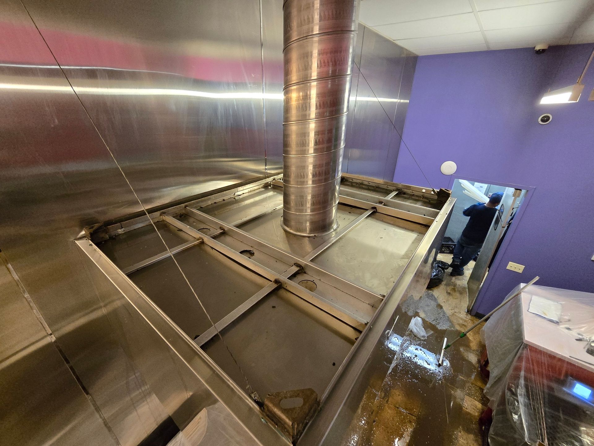 A stainless steel exhaust hood is being installed in a kitchen.