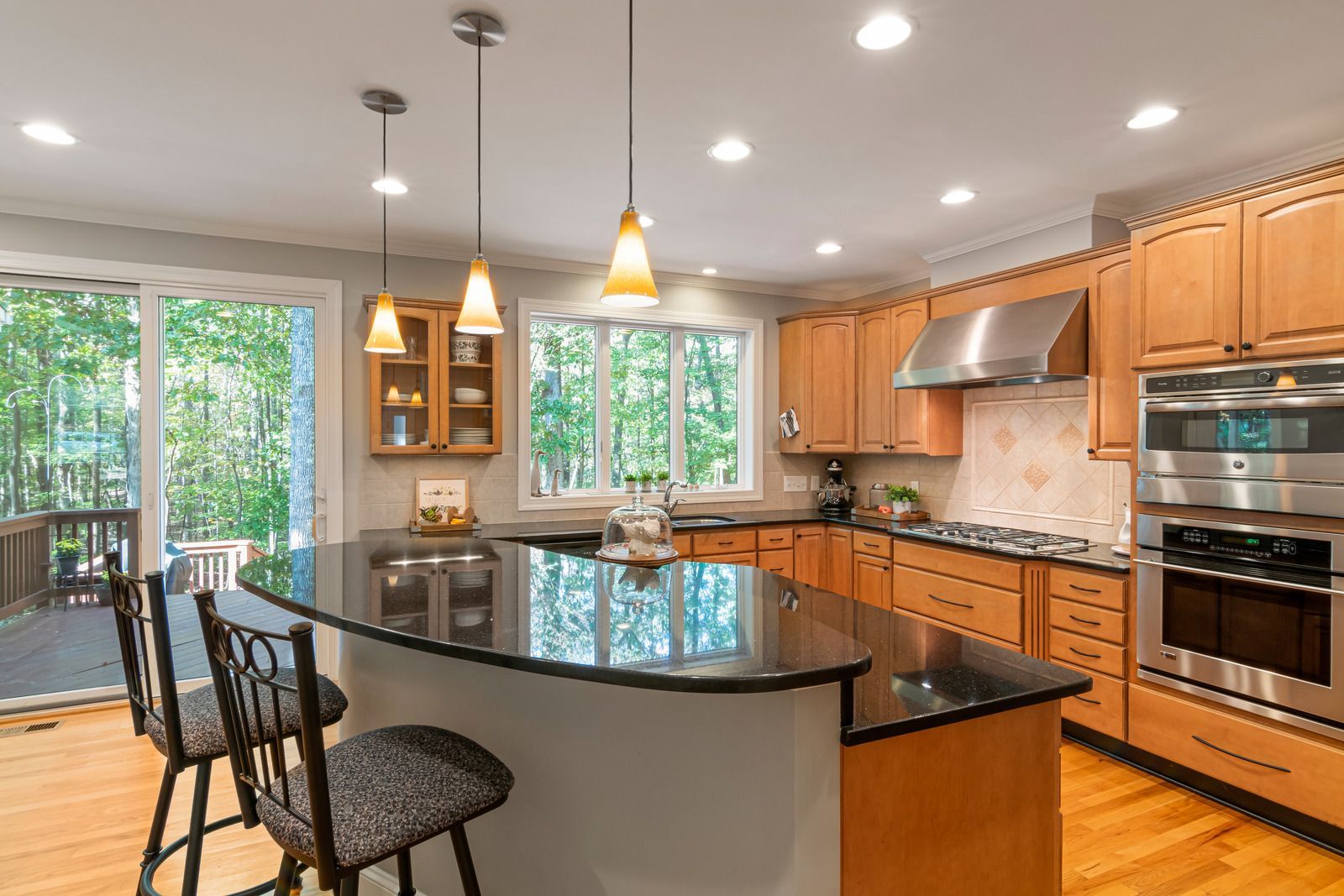 A kitchen with stainless steel appliances, granite counter tops, wooden cabinets and a large
island.