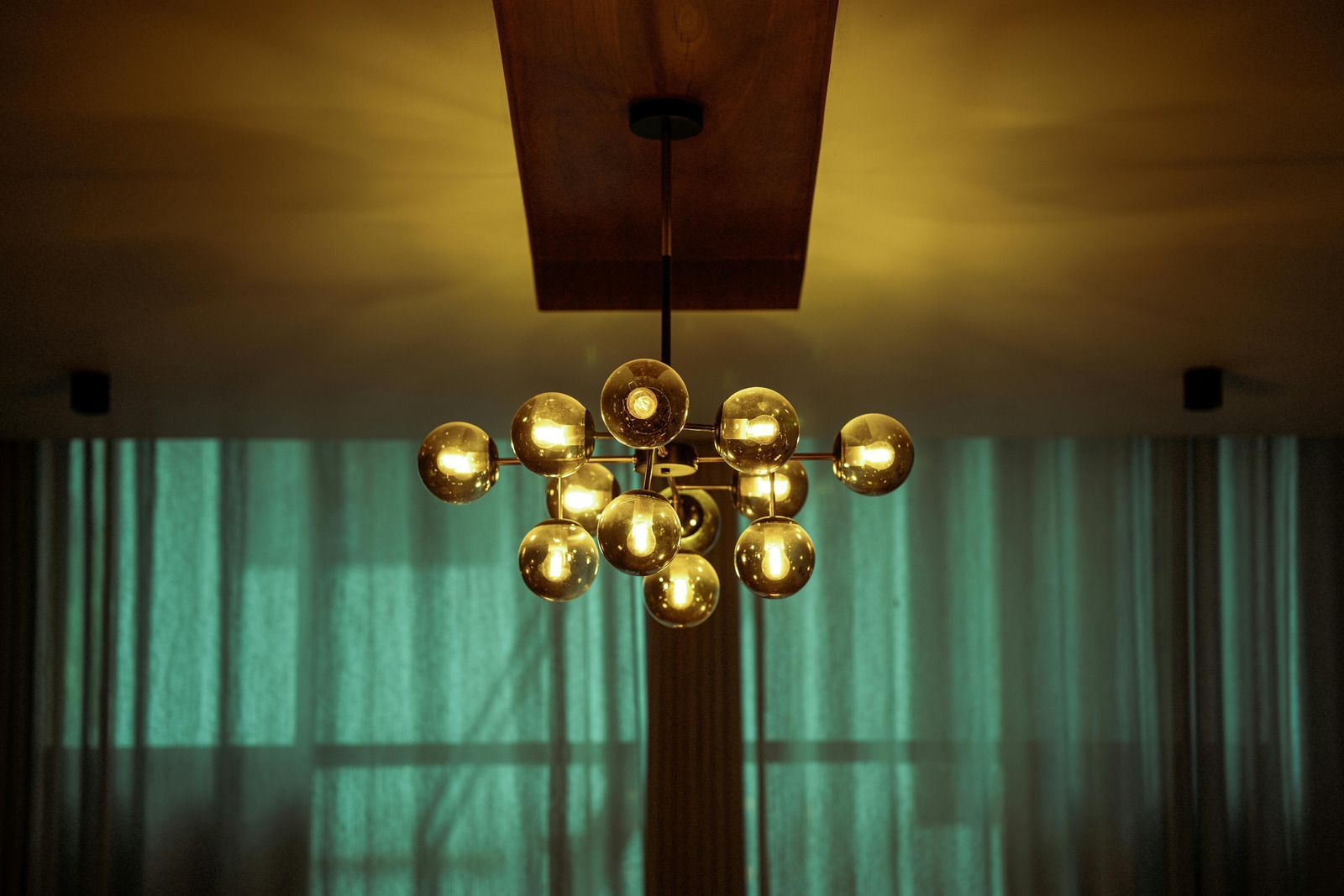 A chandelier is hanging from the ceiling in front of a window.