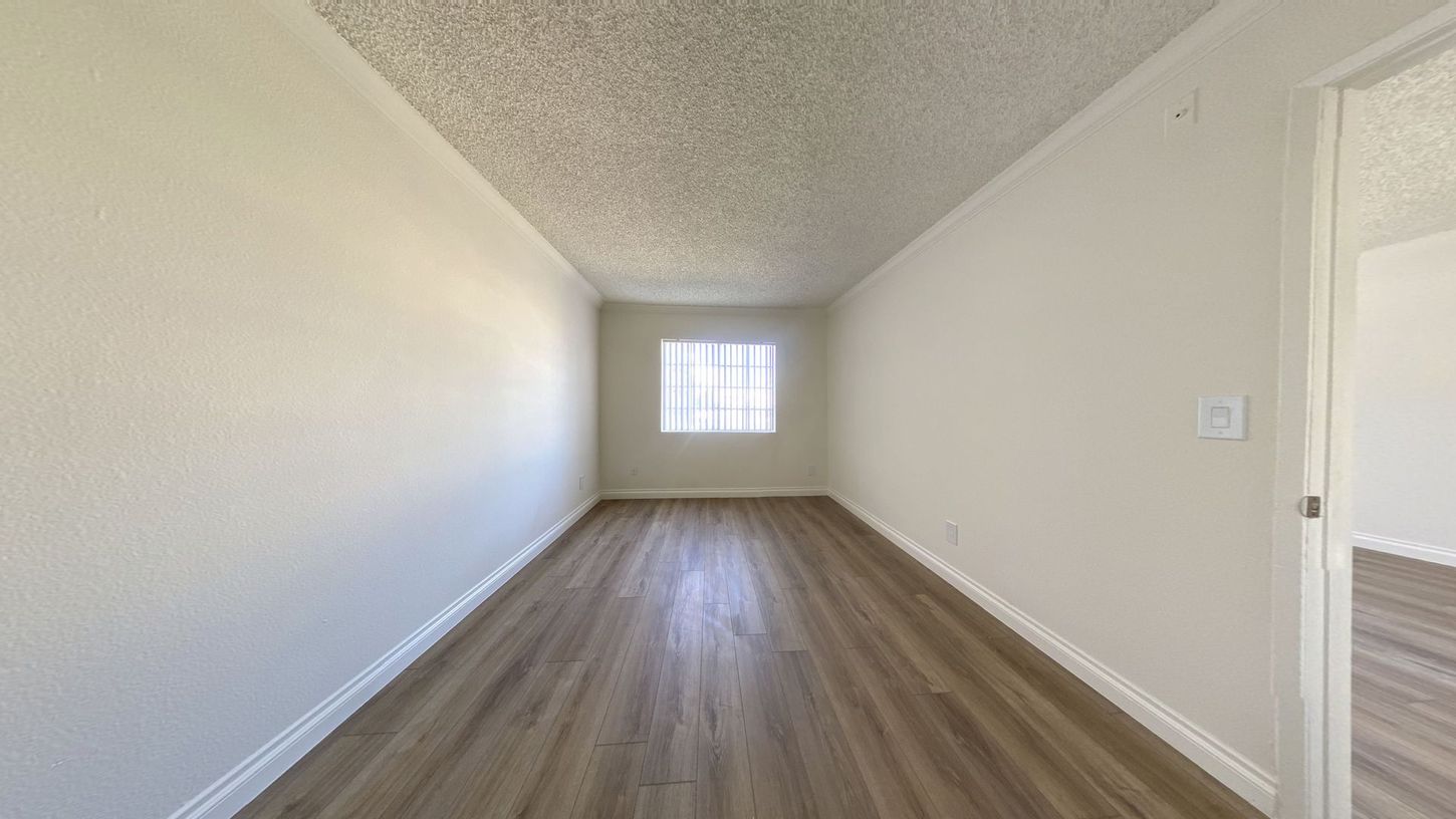 Empty room with light wood floor, white walls, and a window.
