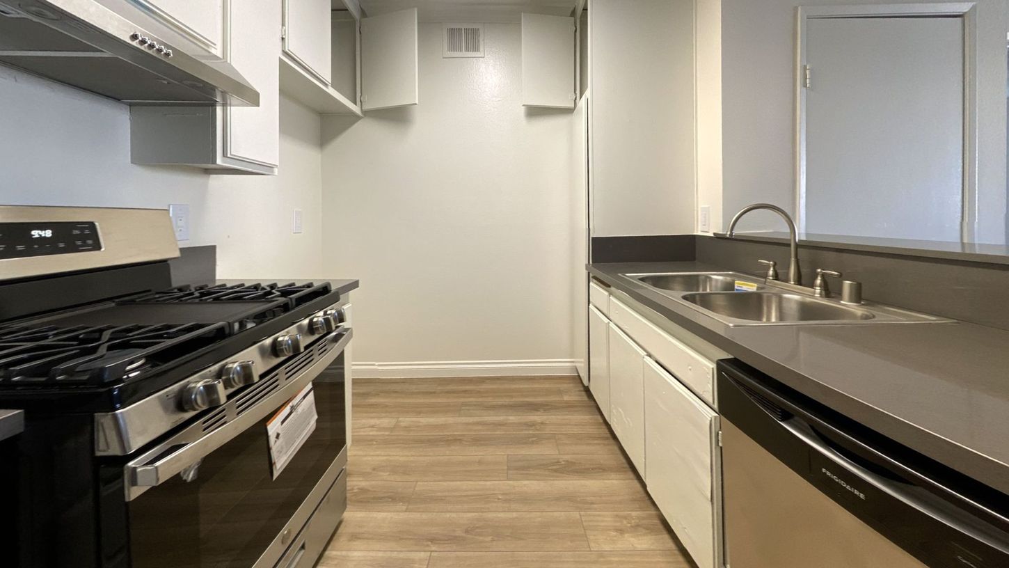 Kitchen with stainless steel appliances, light cabinets, and wood-look flooring.