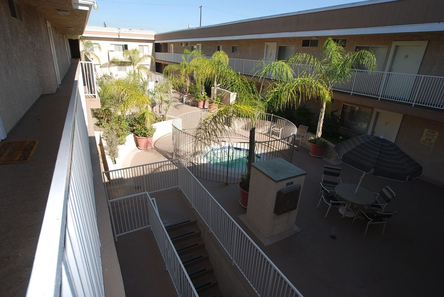 Courtyard view of an apartment complex with pool, palm trees, and outdoor furniture.